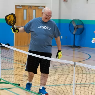 man smiling while playing pickleball at the gateway region ymca